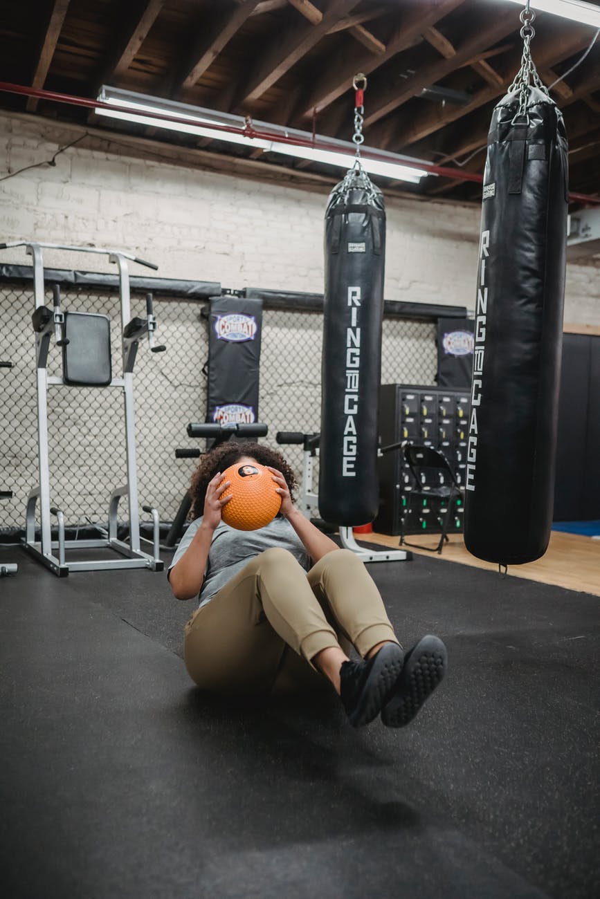 obese black woman doing crunches with weigh ball in gym