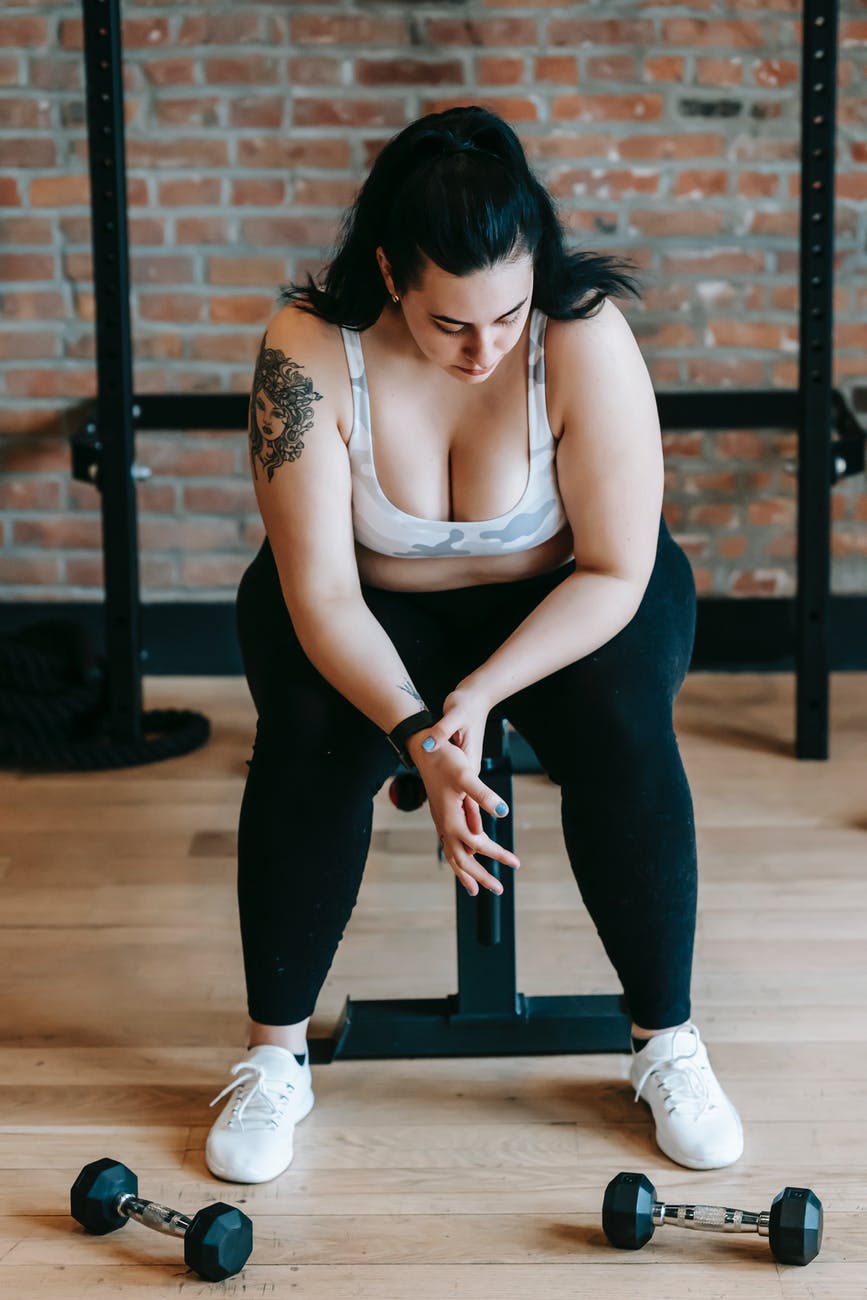 overweight female sitting on bench after exercise with dumbbells