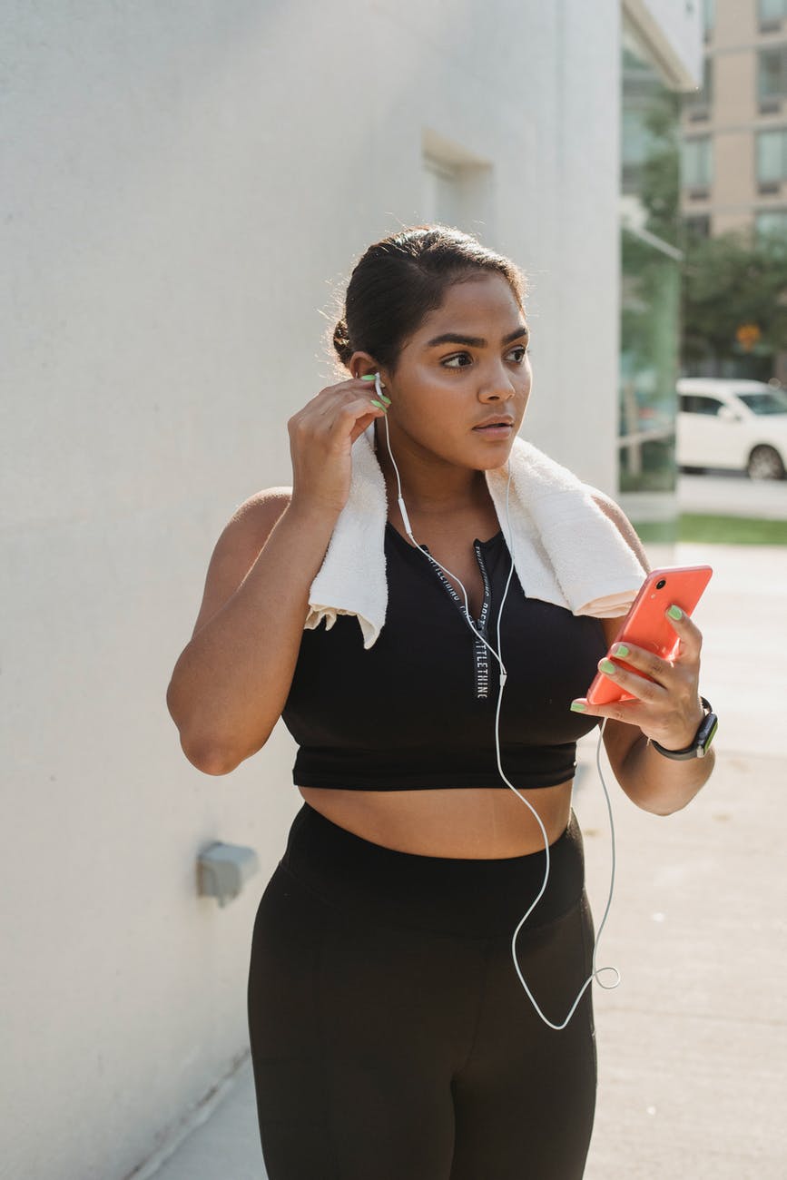 woman in black and white polo shirt holding orange smartphone