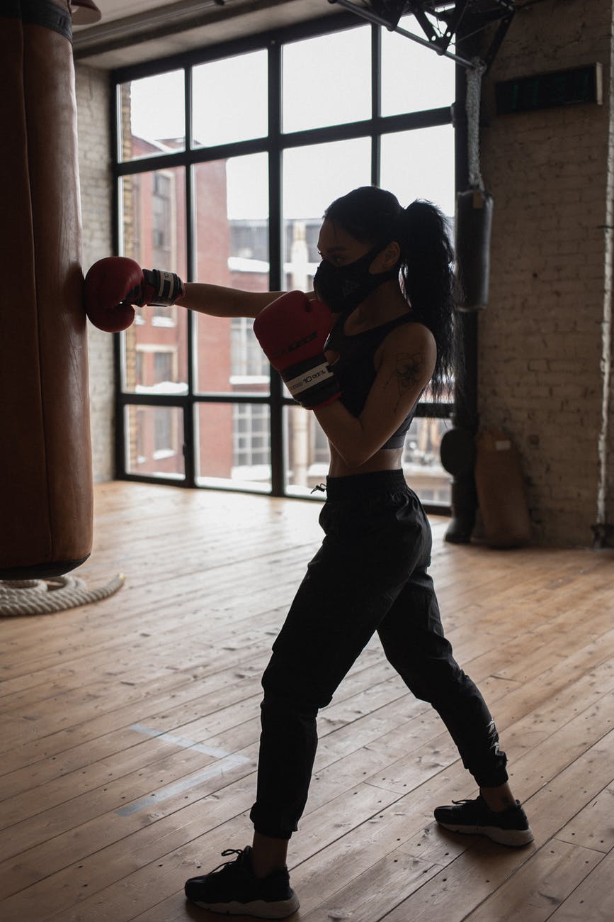 active black boxer punching heavy bag during workout in gymnasium